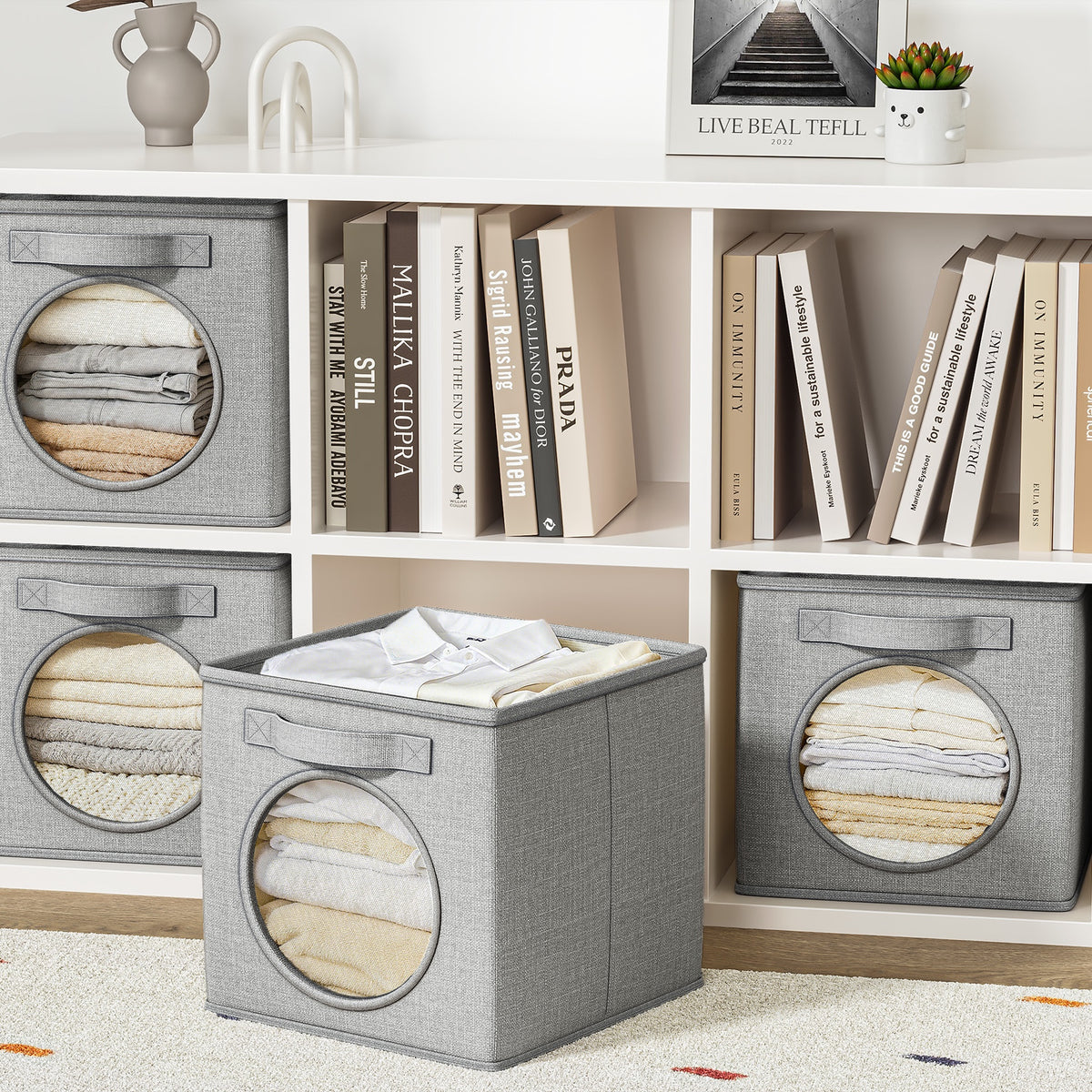 Linen storage cubes on a white shelf with books and folded linens